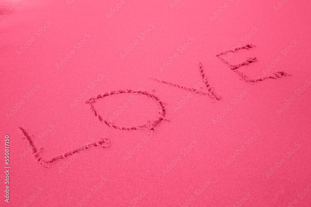 Word love on sandy beach. Background colored in trendy color of 2023 year Viva Magenta