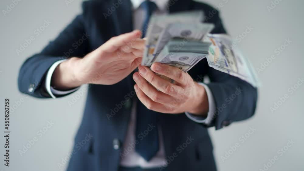 Formally dressed man makes money rain from US dollar bills.
