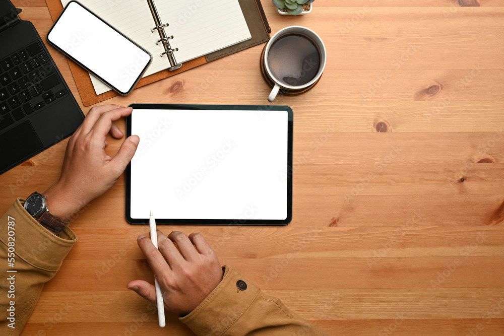 Hipster man hand holding stylus pen and using digital tablet on wooden table. Flat lay, Top view with copy space Hipster man hand holding stylus pen and using digital tablet on wooden table. Flat lay, Top view with copy space