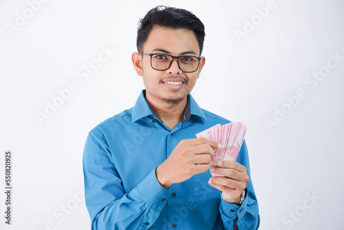 smile or happy asian employee man with glasses holding money wearing blue shirt isolated on white background