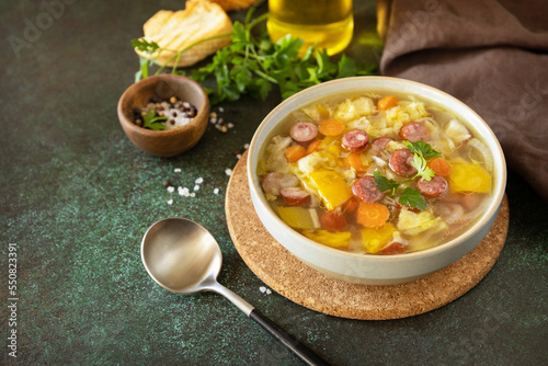 Traditional Zelnacka cabbage soup with sausages and vegetables in a bowl on a stone tabletop. Czech cuisine. Copy space. photo