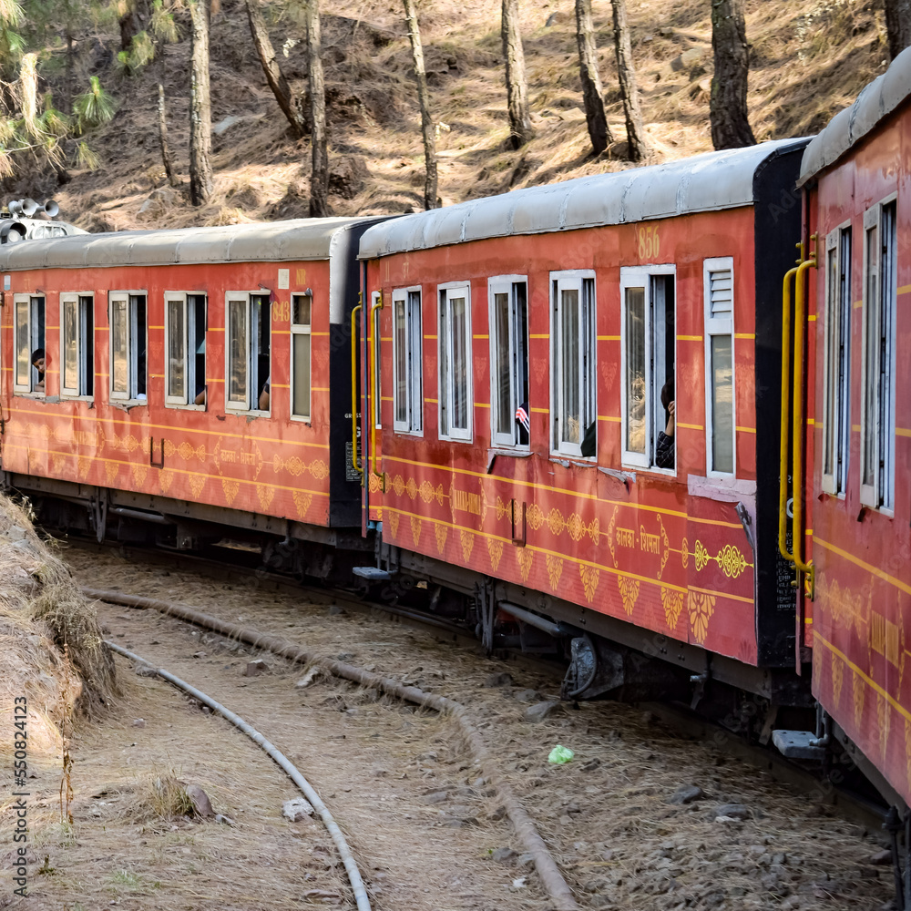 Obraz premium Toy Train moving on mountain slopes, beautiful view, one side mountain, one side valley moving on railway to the hill, among green natural forest. Toy train from Kalka to Shimla in India, Indian Train