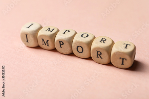 Word Import made of wooden cubes on beige background  closeup