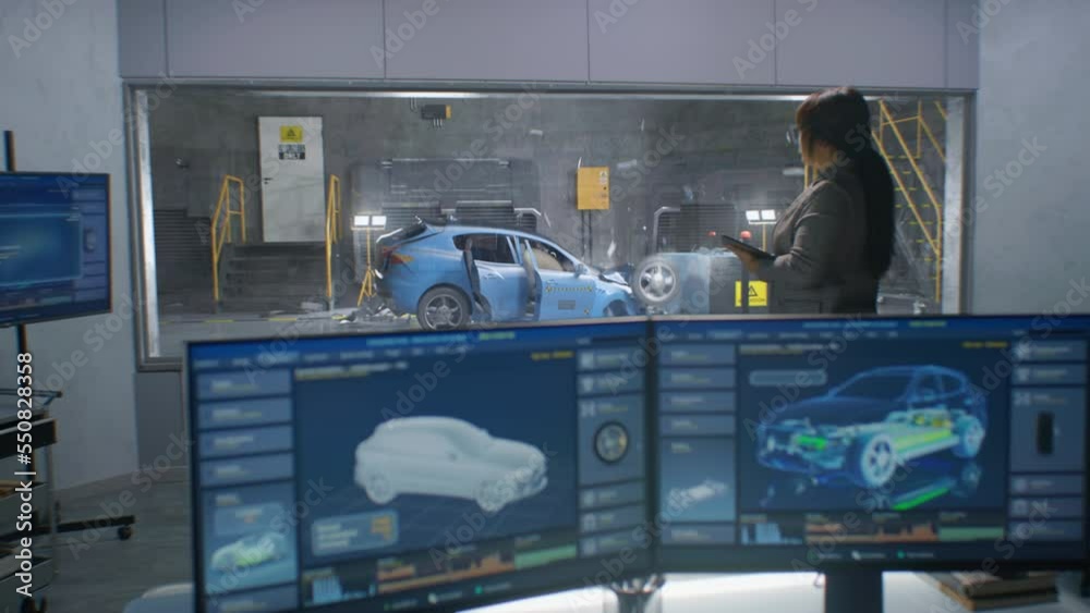 Female and male engineers in experimental crash test laboratory watching process of traffic accident simulation, to get safety parameters of a new electro eco-friendly car body using computer system.
