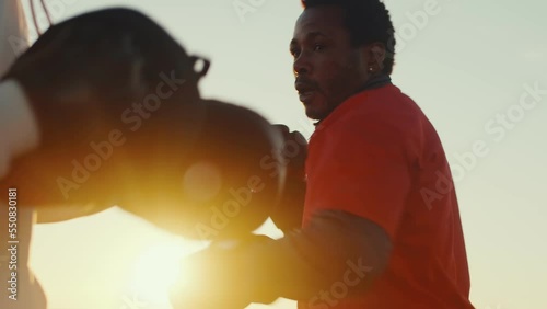 Two black athletes in boxing gloves practice punches and dodges in sparring outdoor on the sunset close up. Two boxers doing few training exercises