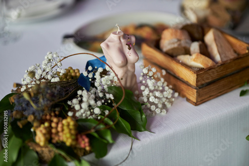 a decorative candle in the form of a female bust stands on the table  a decorative decoration of the festive table