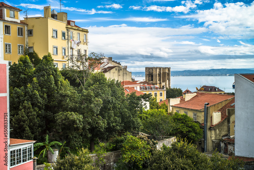 historic buildings of the old town of lisbon. Old colorful buildings, narrow streets, historic churches. Tiled roofs. View from the top of the viewpoint on the tenement houses and monuments. Clouds © Piotr
