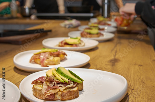 Toast with bacon and avocado on a plate standing on a wooden table