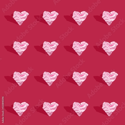 pink crumpled paper hearts on background, viva magenta, color of year 2023. Seamless background