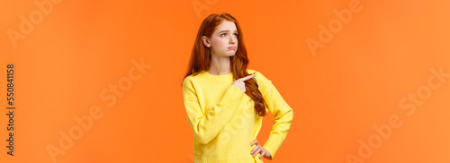 Fotografie, Obraz Jealous or envy sad sulking redhead girl in yellow sweater looking at desired th