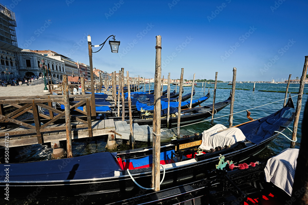 Gondolas docked and tied to poles at the harbour at Saint Marks in Venice, Italy.
