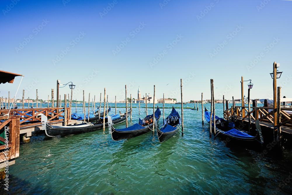 Gondolas docked and tied to poles at the harbour at Saint Marks in Venice, Italy.