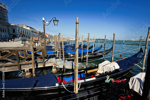 Gondolas docked and tied to poles at the harbour at Saint Marks in Venice, Italy. © AS Photo Family