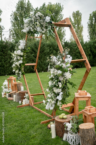 Wedding ceremony. Very beautiful and stylish hexagonal wedding arch  decorated with various fresh flowers  standing in the garden.