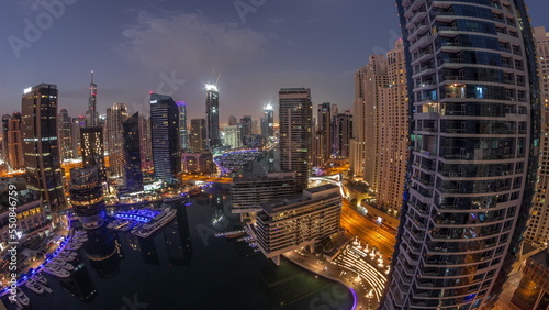 Aerial view to Dubai marina skyscrapers around canal with floating boats night to day timelapse © neiezhmakov
