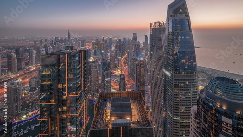 Skyline panoramic view of Dubai Marina showing canal surrounded by skyscrapers along shoreline day to night timelapse. DUBAI, UAE