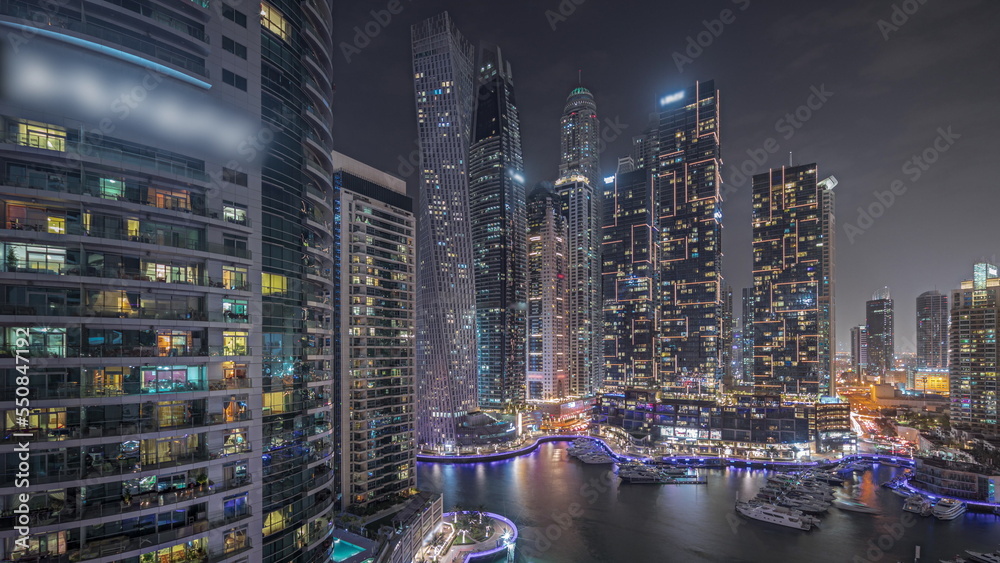 Panorama showing Dubai marina tallest skyscrapers and yachts in harbor aerial night timelapse. Panorama showing Dubai marina tallest skyscrapers and yachts in harbor aerial night timelapse.