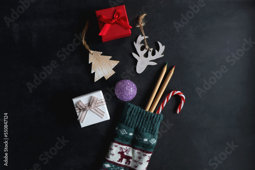 Christmas stocking filled with decorations, small presents, sweets and toys. Dark background, top view.