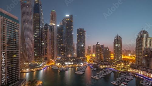 Fototapeta Naklejka Na Ścianę i Meble -  Dubai marina tallest skyscrapers and yachts in harbor aerial night to day timelapse.