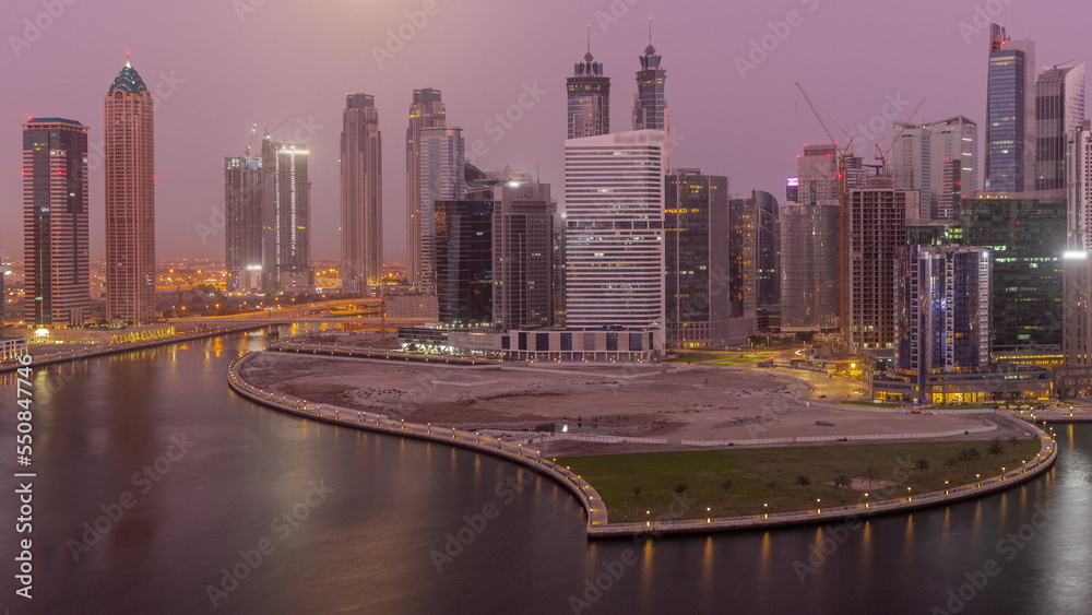 Fototapeta premium Cityscape of skyscrapers in Dubai Business Bay with water canal aerial night to day timelapse