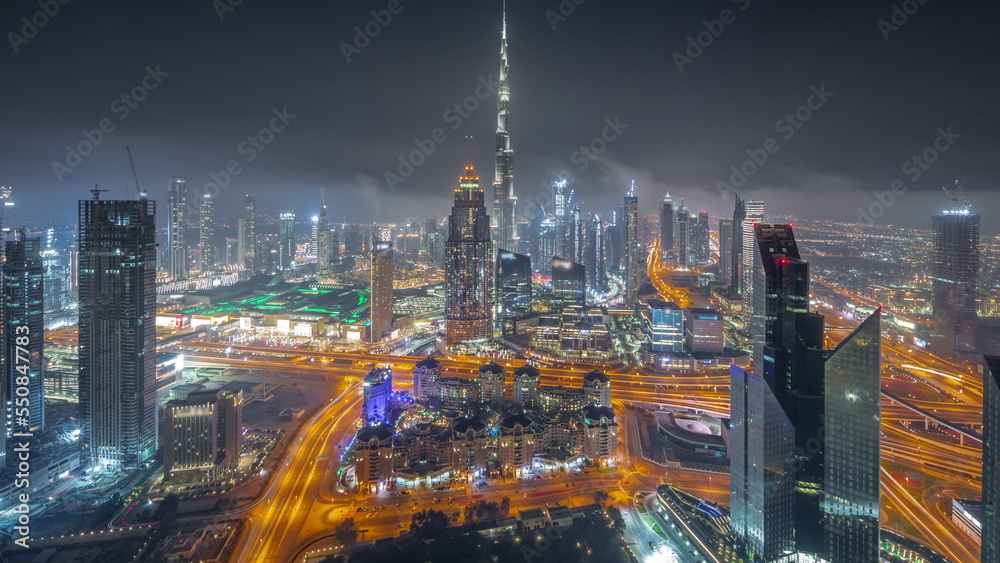 Fototapeta premium Aerial view of tallest towers in Dubai Downtown skyline and highway all night timelapse.