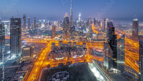 Aerial view of tallest towers in Dubai Downtown skyline and highway night to day timelapse.