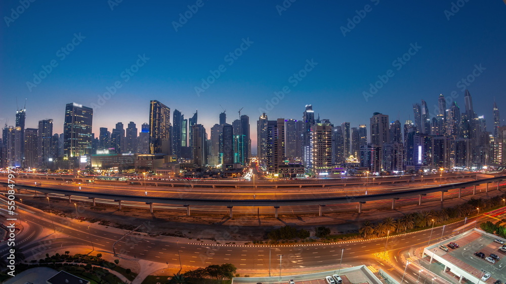 Panorama of Dubai Marina skyscrapers and Sheikh Zayed road with metro railway aerial day to night timelapse, United Arab Emirates
