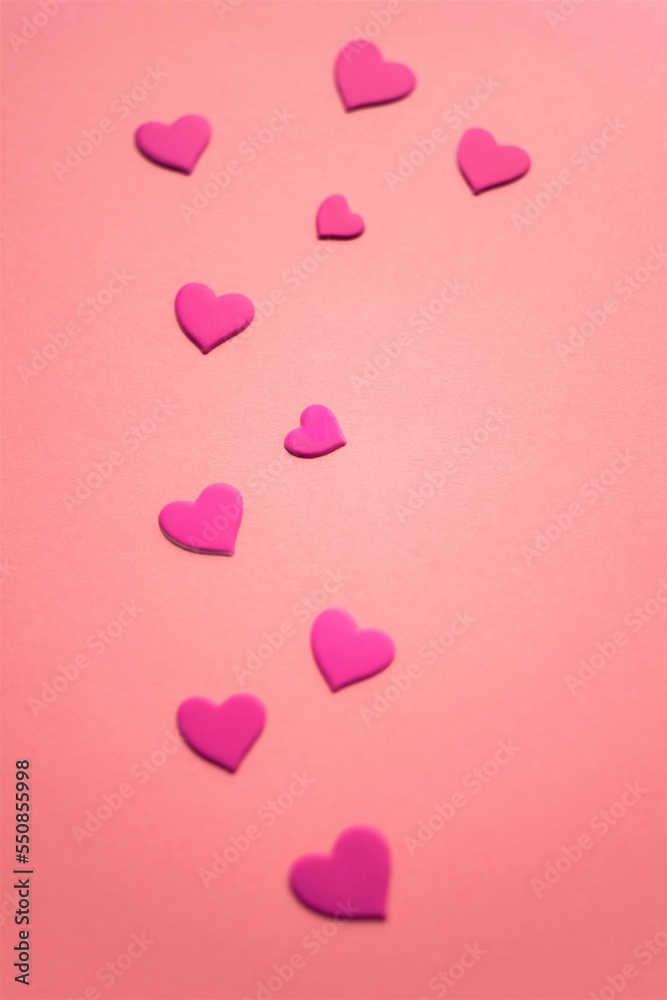 Pink sticker hearts on pale red paper table