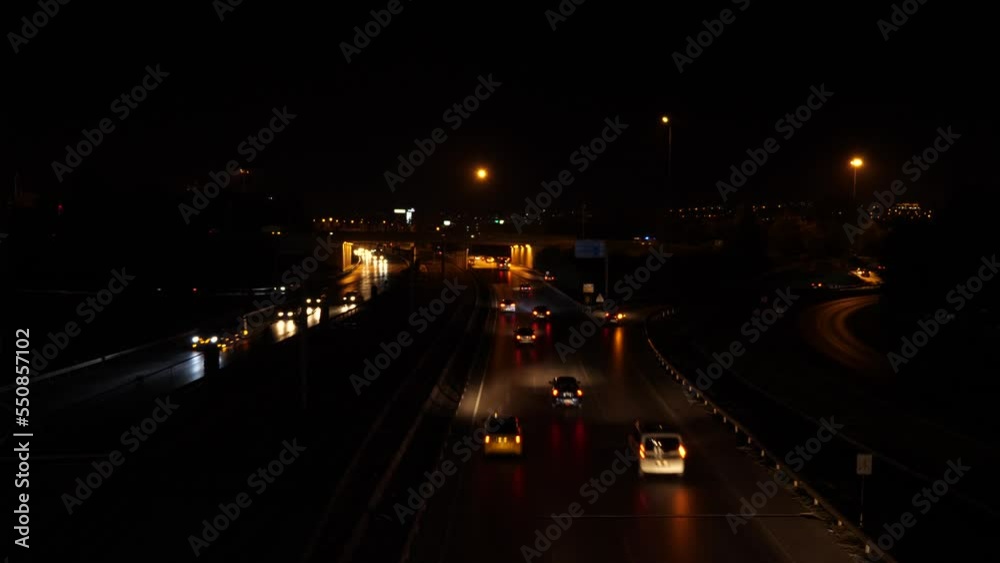 Night road with lots of cars on the outskirts of a big city. Cars with lights and parking lights driving on the road and interchange in the city. Nighttime traffic Night road with lots of cars on the outskirts of a big city. Cars with lights and parking lights driving on the road and interchange in the city. Nighttime traffic