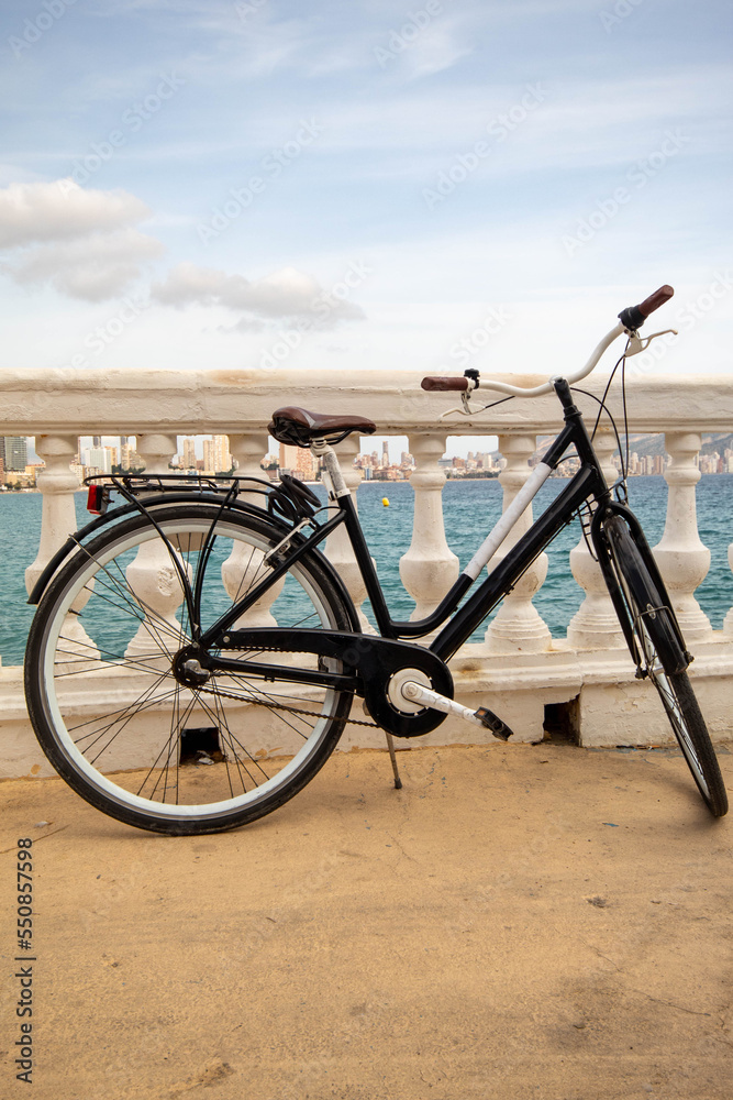 Bicicleta alquilada con la que los turistas pasean por las calles de Benidorm con su ciudad de fondo bajo un precioso día soleado.