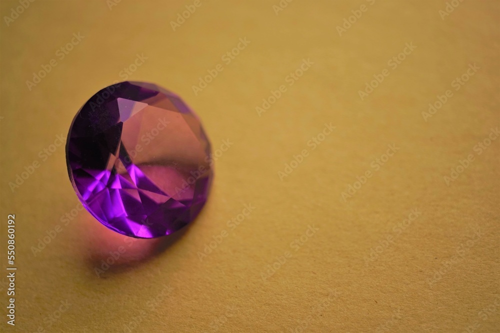 Violet crystal with facets on a brown table Violet crystal with facets on a brown table