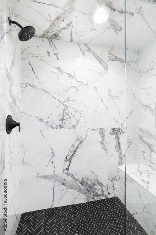A luxury shower with marble tiled walls, black herringbone tiled ...