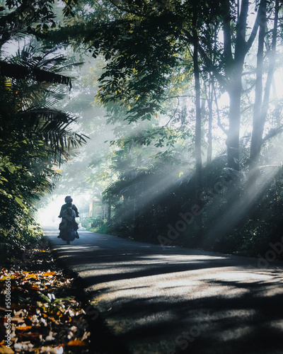 Canvas Print a father and son riding a motorbike through a green forest with beautiful and ep