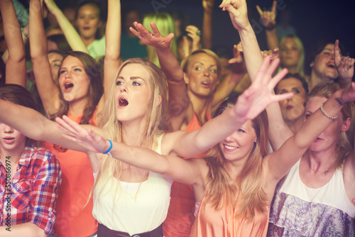 Concert, music festival and crowd of women or audience in night club, dance event and singing celebration with lights, disco and club lifestyle. Fans, group of people or youth at rave or techno party