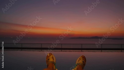 Close-up of legs in the swimming pool on the rooftop, sunset