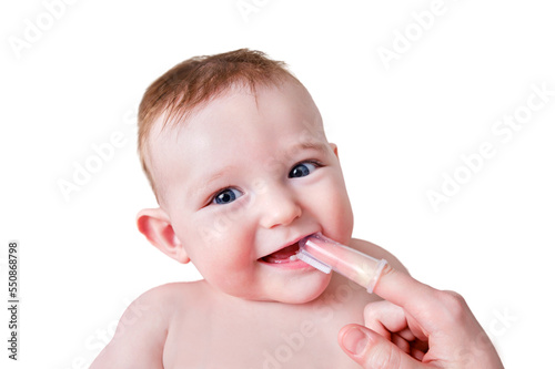 Mother hands brushing teeth with a finger brush of a happy infant baby, isolated on a white background. Mom doing oral hygiene to a smiling toddler kid, six to seven months old