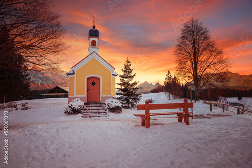 Fototapeta pilgrimage chapel in snowy winter landscape, colorful sunset scenery upper bavar