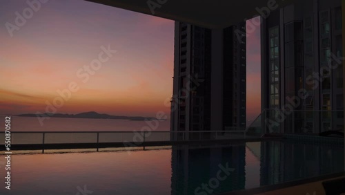 Swimming pool on a roof with a view on a sea and skyscraper at sunset