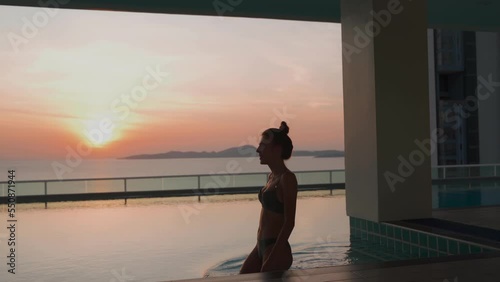 Beautiful woman in a swimming pool on a roof at sunset