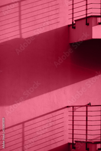 Viva magenta wall with balconies with shadows. Minimal abstract concept. Color trend year 2023.