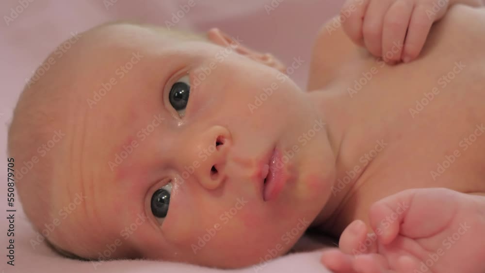 Close-up of face of newborn baby. Caucasian child laying on the bed and looking around. Slow motion shot Close-up of face of newborn baby. Caucasian child laying on the bed and looking around. Slow motion shot