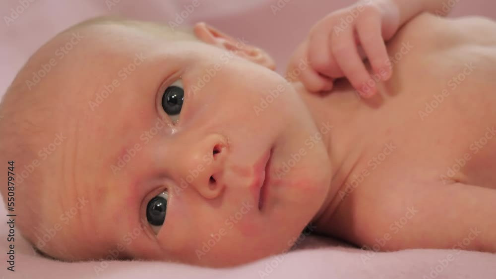 Close-up of face of newborn baby. Caucasian child laying on the bed and looking around. Slow motion shot Close-up of face of newborn baby. Caucasian child laying on the bed and looking around. Slow motion shot