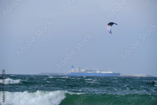 Kitesurfing, riding board waves during storm holding to flying kite.