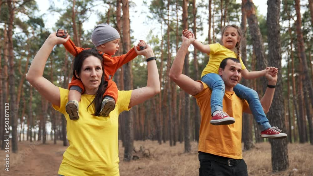 Happy family. Pplay with children in forest park. Children on shoulders of father, mother. Walking with children in nature in park. Happy father, mother with children together outdoors in park.