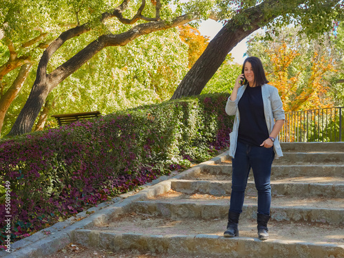 woman in gray blazer walking down park steps talking on cell phone photo