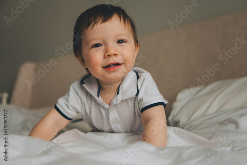portrait of a smiling baby of one year on the bed at home