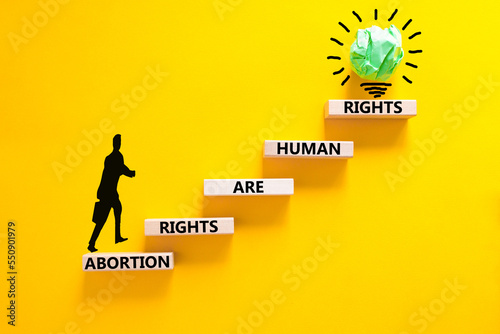 Abortion rights symbol. Concept words Abortion rights are human rights on wooden blocks. Businessman icon. Beautiful yellow background. Business medical abortion rights concept. Copy space.