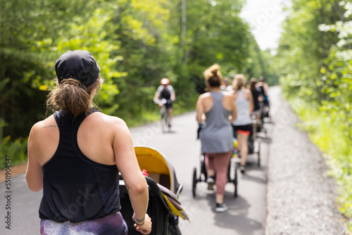 Photo taken from the back of group of mothers participating in outdoor fitness session to rebuild muscles after giving birth to their babies