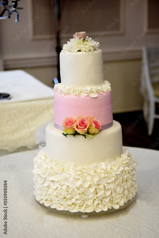 white pink wedding cake with roses on a table white pink wedding cake with roses on a table