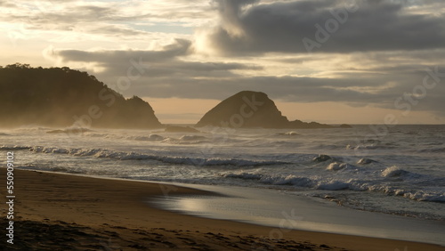 Sunrise casting a golden glow over an islet and the beach in Zipolite  Mexico